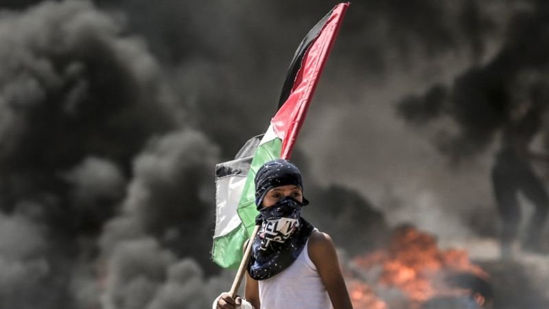 গাজার ইসলায়েলি সীমান্তে ফিলিস্তিনি পতাকা হাতে এক কিশোর